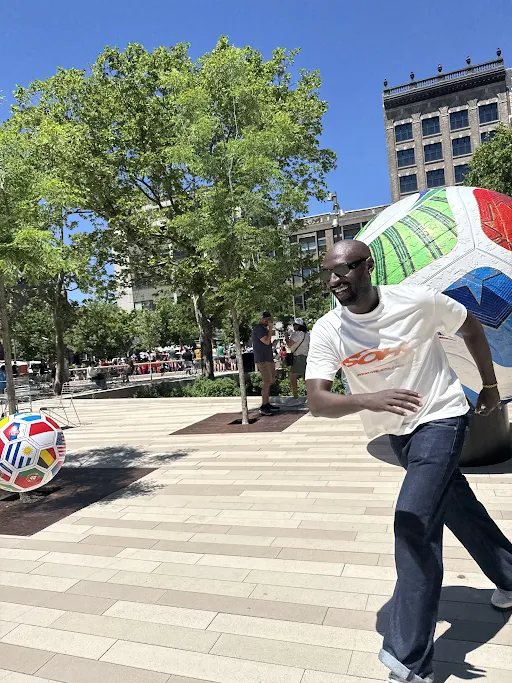 Running past a giant painted football in a sunny plaza
