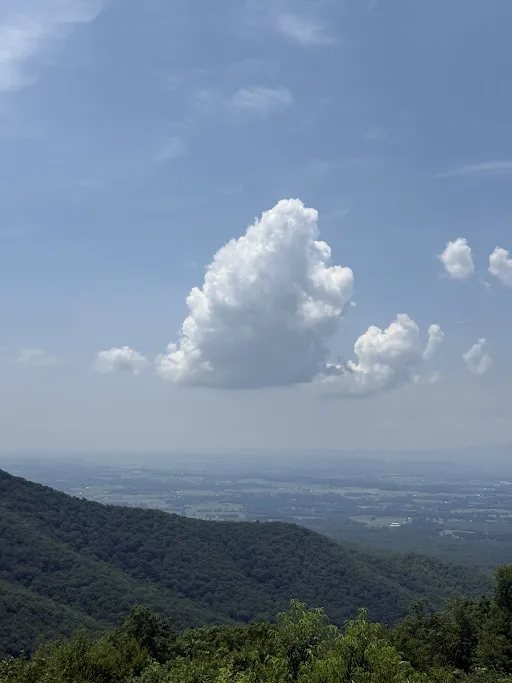 A single large cloud over a blue mountain valley