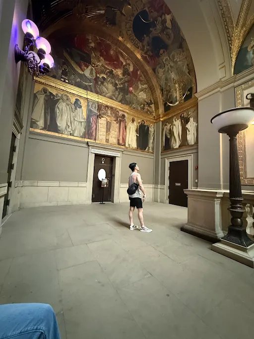 Standing alone in a gallery under painted arches