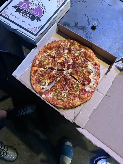 An open pizza box on a car hood at night