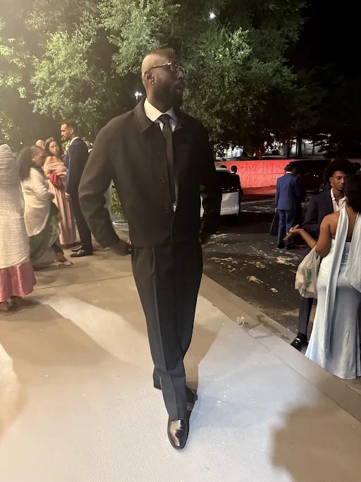 Walking out of a venue at night in a dark suit