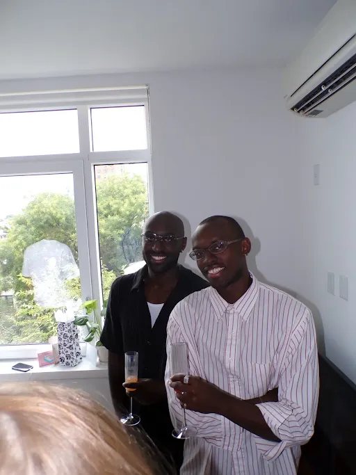 Two friends with champagne glasses by a bright window